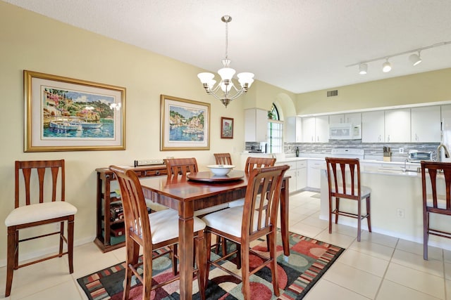 tiled dining area with a textured ceiling and a notable chandelier