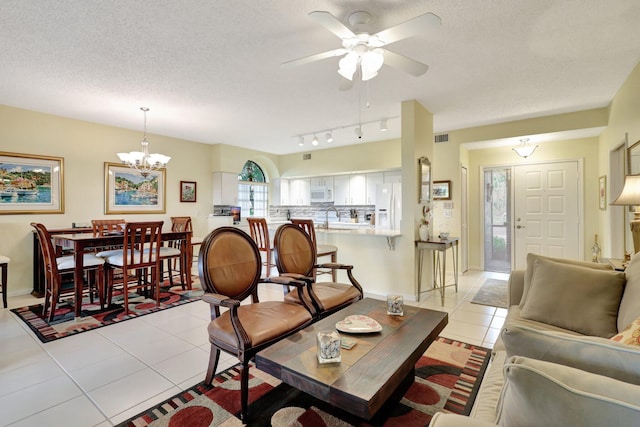 tiled living room with rail lighting, ceiling fan with notable chandelier, sink, and a textured ceiling