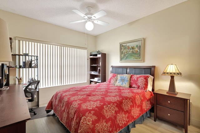 bedroom with ceiling fan, a textured ceiling, and light wood-type flooring