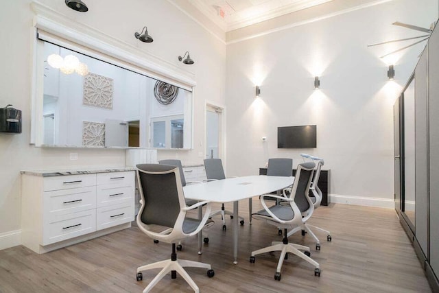 office with light hardwood / wood-style floors, crown molding, and a high ceiling