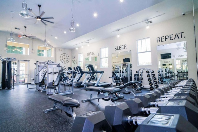 gym featuring ceiling fan, a towering ceiling, track lighting, and a healthy amount of sunlight