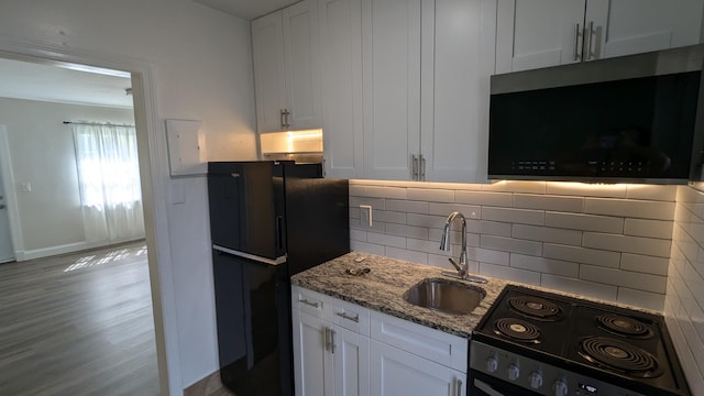 kitchen featuring light hardwood / wood-style floors, white cabinetry, and black appliances