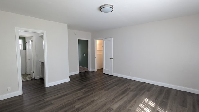 unfurnished bedroom featuring a closet, dark hardwood / wood-style flooring, and a walk in closet