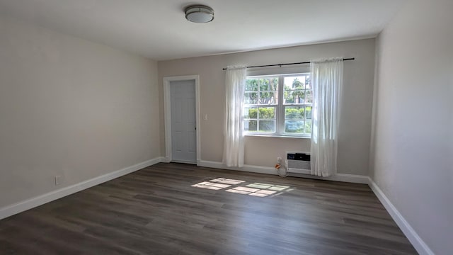 spare room featuring dark hardwood / wood-style flooring and an AC wall unit