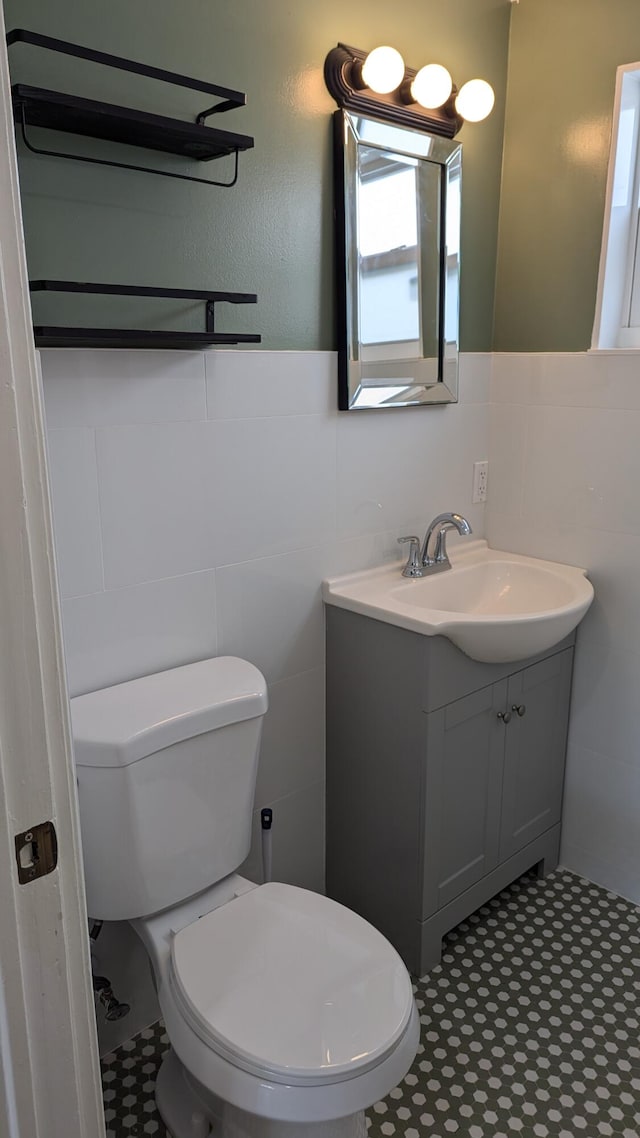 bathroom featuring vanity, tile walls, and toilet