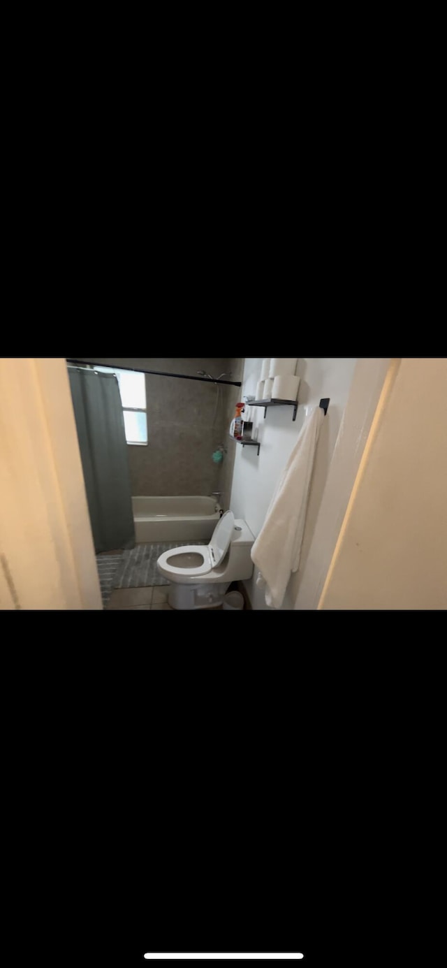 bathroom with shower / bath combo, tile patterned floors, and toilet