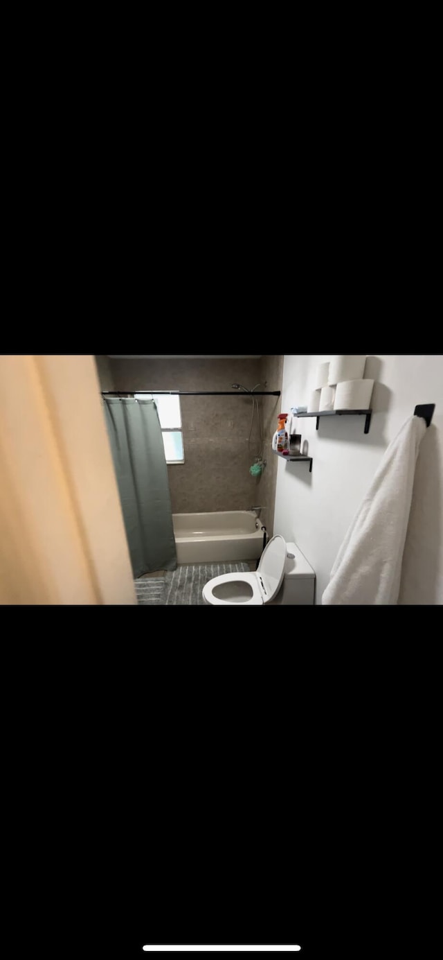 bathroom featuring toilet and shower / bathtub combination with curtain