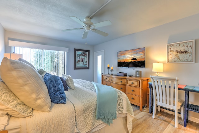 bedroom featuring ceiling fan, a textured ceiling, and light wood-type flooring