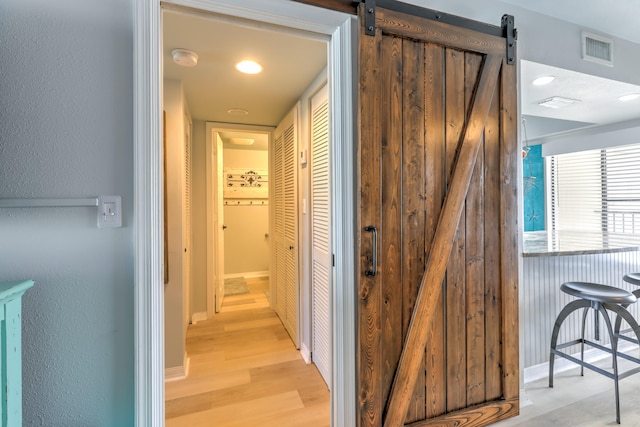 hall with a barn door and light wood-type flooring