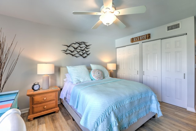 bedroom featuring hardwood / wood-style flooring, ceiling fan, and two closets