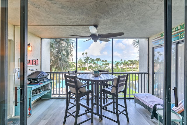 sunroom / solarium featuring ceiling fan and a water view