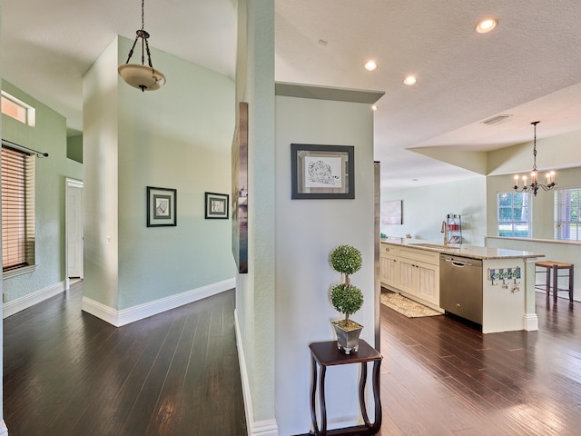 corridor featuring a textured ceiling, dark hardwood / wood-style flooring, a chandelier, and sink