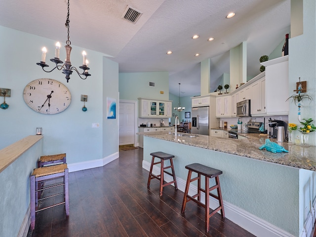 kitchen featuring hanging light fixtures, kitchen peninsula, high vaulted ceiling, stainless steel appliances, and dark hardwood / wood-style flooring