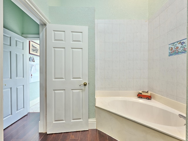 bathroom featuring hardwood / wood-style flooring, a bathtub, and a textured ceiling