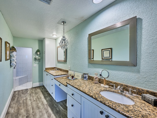 bathroom featuring vanity, hardwood / wood-style floors, a textured ceiling, and tiled shower