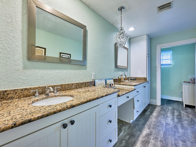 bathroom with an inviting chandelier, vanity, hardwood / wood-style floors, and a textured ceiling