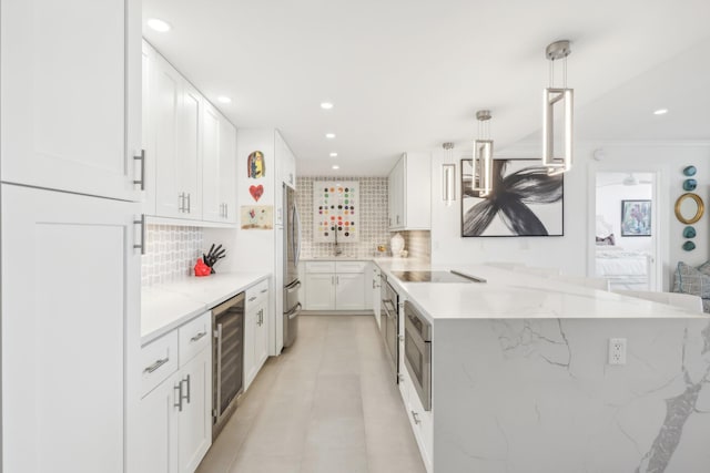 kitchen with backsplash, white cabinets, hanging light fixtures, stainless steel refrigerator, and beverage cooler