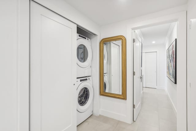 washroom with light tile patterned flooring, ornamental molding, and stacked washer / dryer