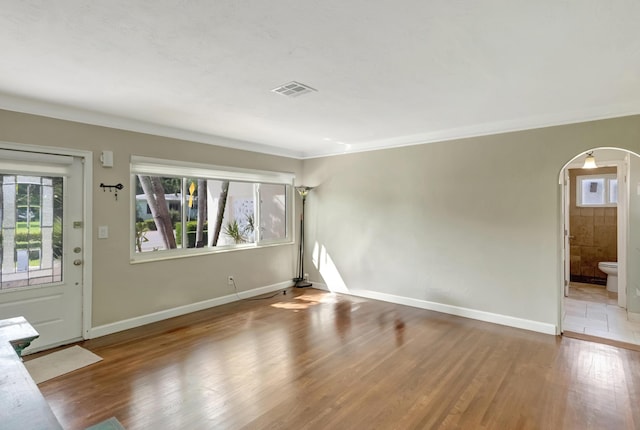 entryway featuring arched walkways, baseboards, visible vents, and wood finished floors