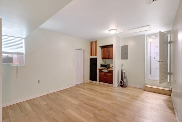 unfurnished living room featuring light hardwood / wood-style floors, cooling unit, and electric panel