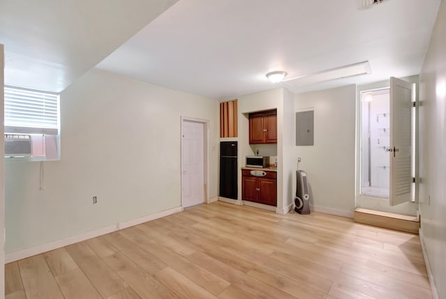 unfurnished living room featuring light wood-style floors, baseboards, cooling unit, and electric panel