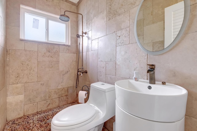 bathroom with a sink, a tile shower, and toilet