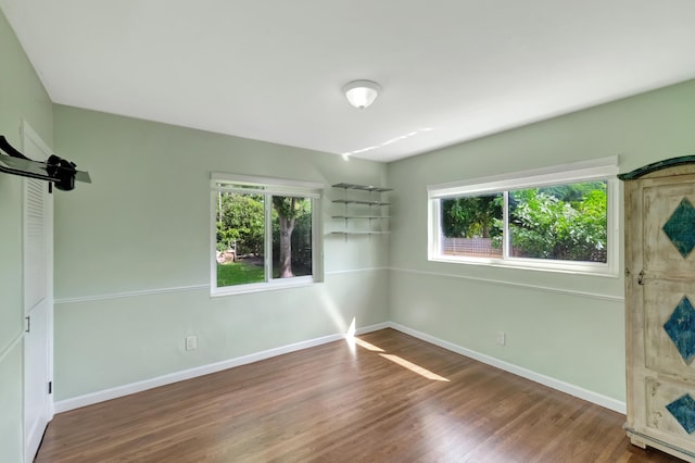 unfurnished bedroom featuring baseboards, multiple windows, and wood finished floors