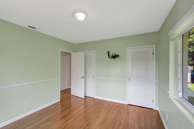 unfurnished bedroom with hardwood / wood-style floors and two closets