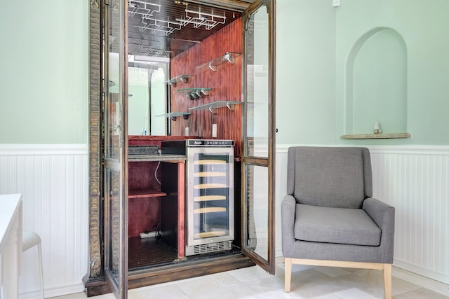 unfurnished room with wine cooler, bar, and tile patterned flooring