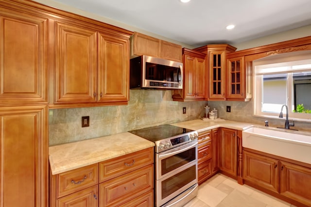 kitchen featuring tasteful backsplash, light tile patterned floors, light stone countertops, sink, and stainless steel appliances