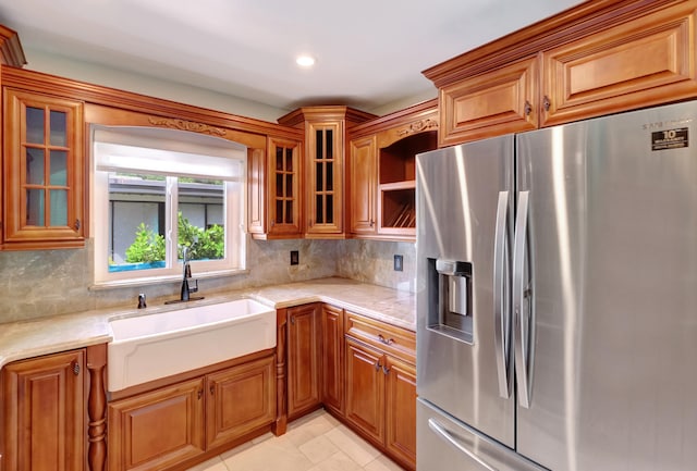 kitchen featuring sink, light stone counters, tasteful backsplash, and stainless steel fridge with ice dispenser