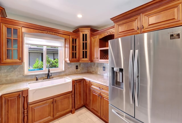 kitchen featuring stainless steel fridge, tasteful backsplash, brown cabinets, and a sink