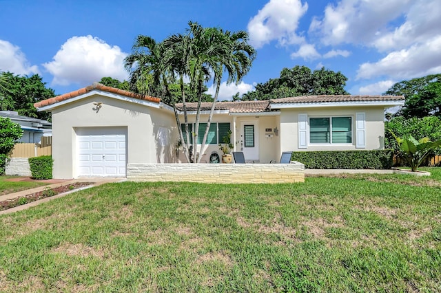 view of front of house featuring stucco siding, a tiled roof, a front yard, and a garage