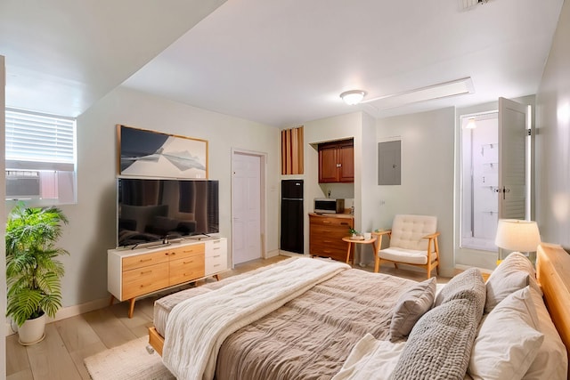 bedroom with electric panel, light hardwood / wood-style floors, and black fridge