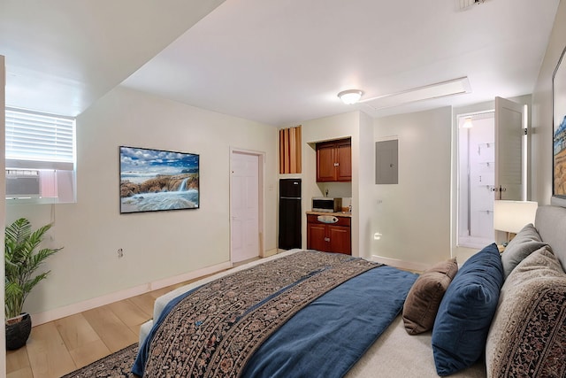 bedroom with electric panel, light wood-type flooring, baseboards, cooling unit, and black fridge