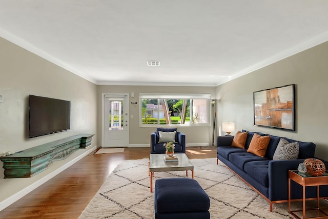 living room with crown molding, baseboards, visible vents, and wood finished floors