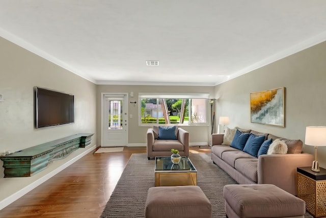 living area with crown molding, baseboards, wood finished floors, and visible vents