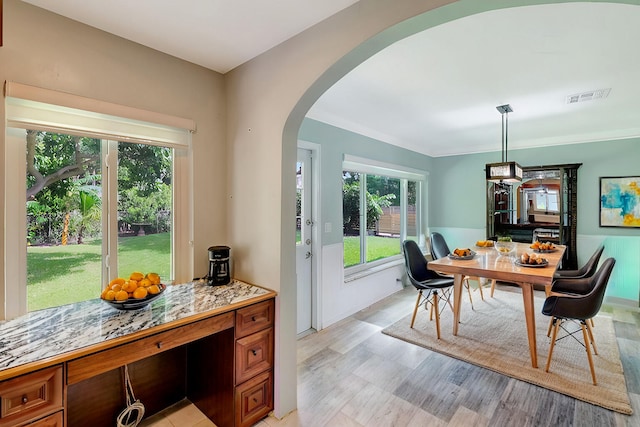 dining area featuring arched walkways, light wood finished floors, and visible vents