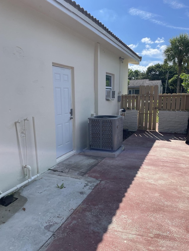 exterior space with central air condition unit, a gate, stucco siding, and a tiled roof