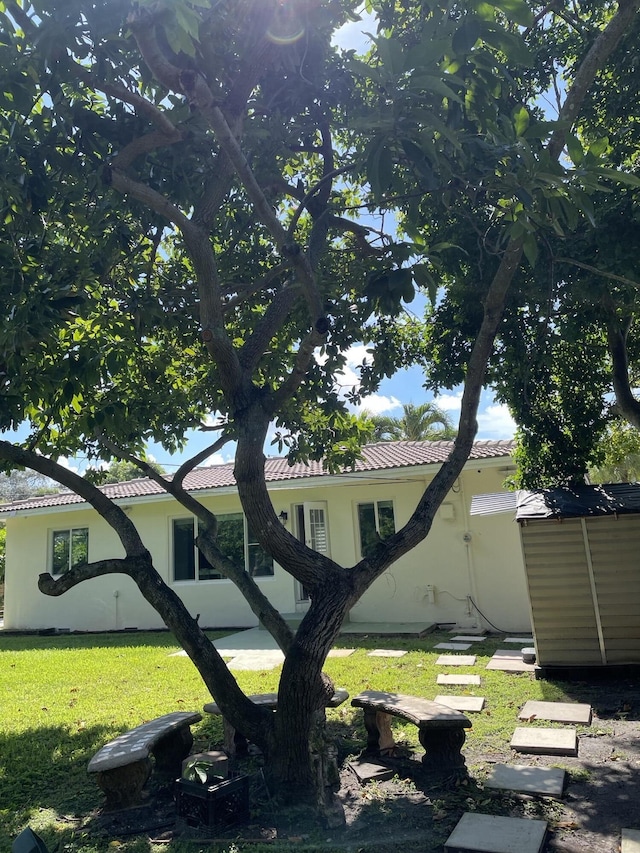 exterior space with a lawn, stucco siding, and a tiled roof