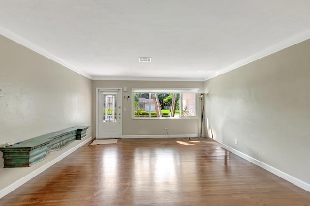 unfurnished room with crown molding, baseboards, wood finished floors, and visible vents