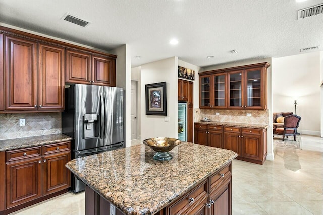 kitchen featuring sink, dishwasher, light stone countertops, a kitchen island, and decorative backsplash