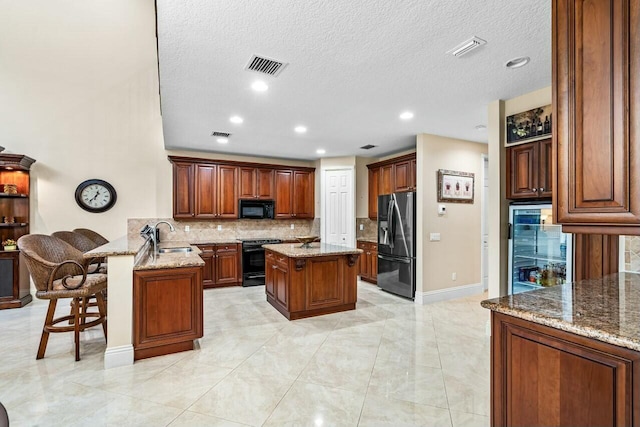 kitchen featuring tasteful backsplash, a kitchen island, light stone counters, and stainless steel fridge with ice dispenser