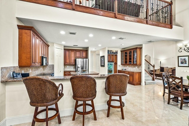 kitchen with a breakfast bar, kitchen peninsula, a kitchen island, light stone countertops, and black appliances