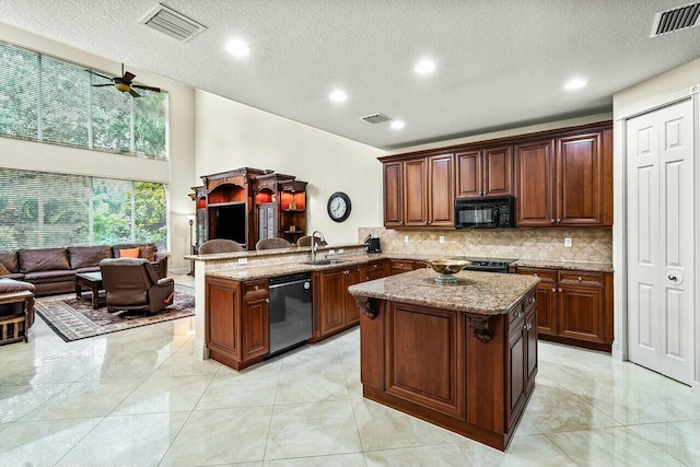 kitchen featuring sink, black appliances, kitchen peninsula, and a kitchen island