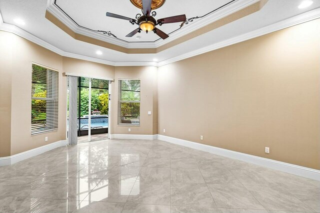 spare room featuring crown molding, ceiling fan, and a tray ceiling