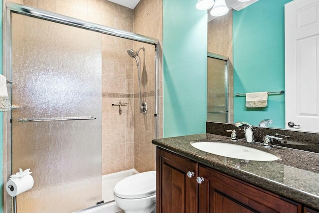 bathroom featuring a shower with door, vanity, and toilet