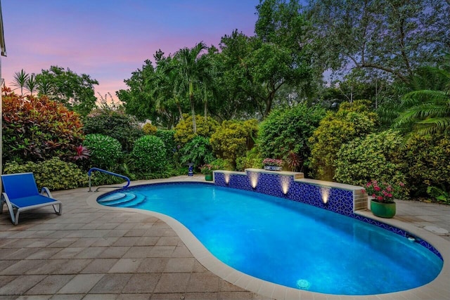 pool at dusk featuring a patio area