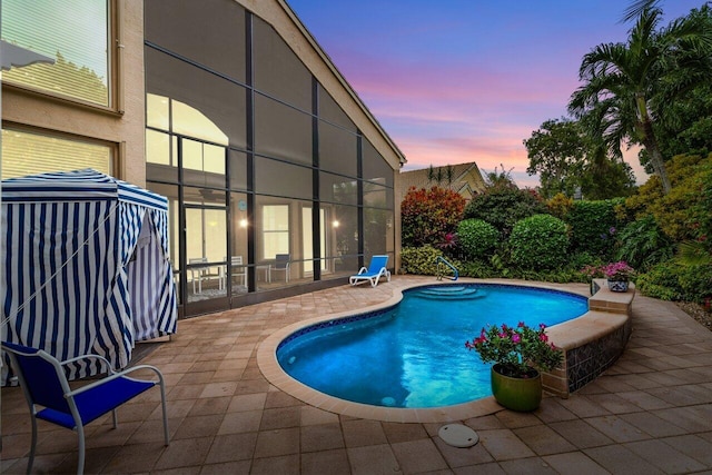 pool at dusk with a patio area