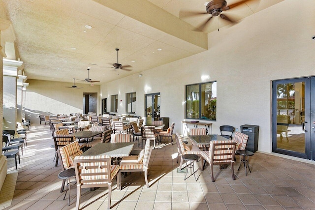 dining room with a high ceiling, light tile patterned floors, ceiling fan, and french doors